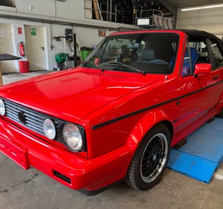 Rotes Cabriolet-Auto in einer Werkstatt auf einer blauen Hebebühne.